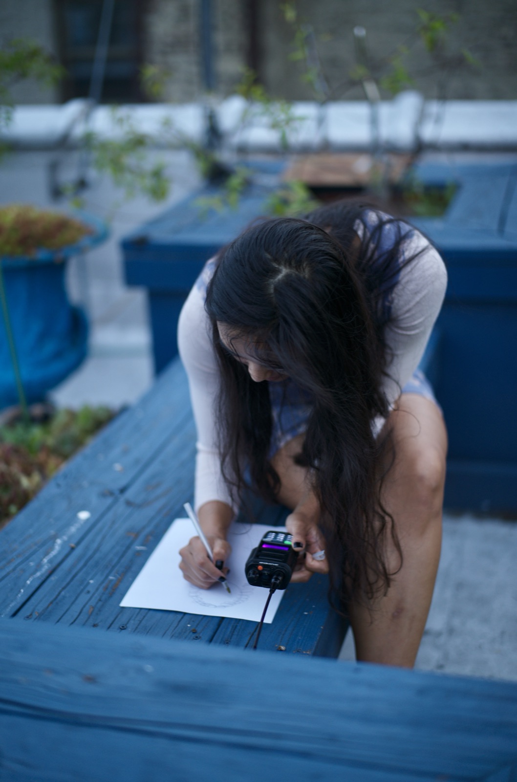 A participant sketches on paper while keying a radio — the partner relay game, where one person describes and the other draws without looking.