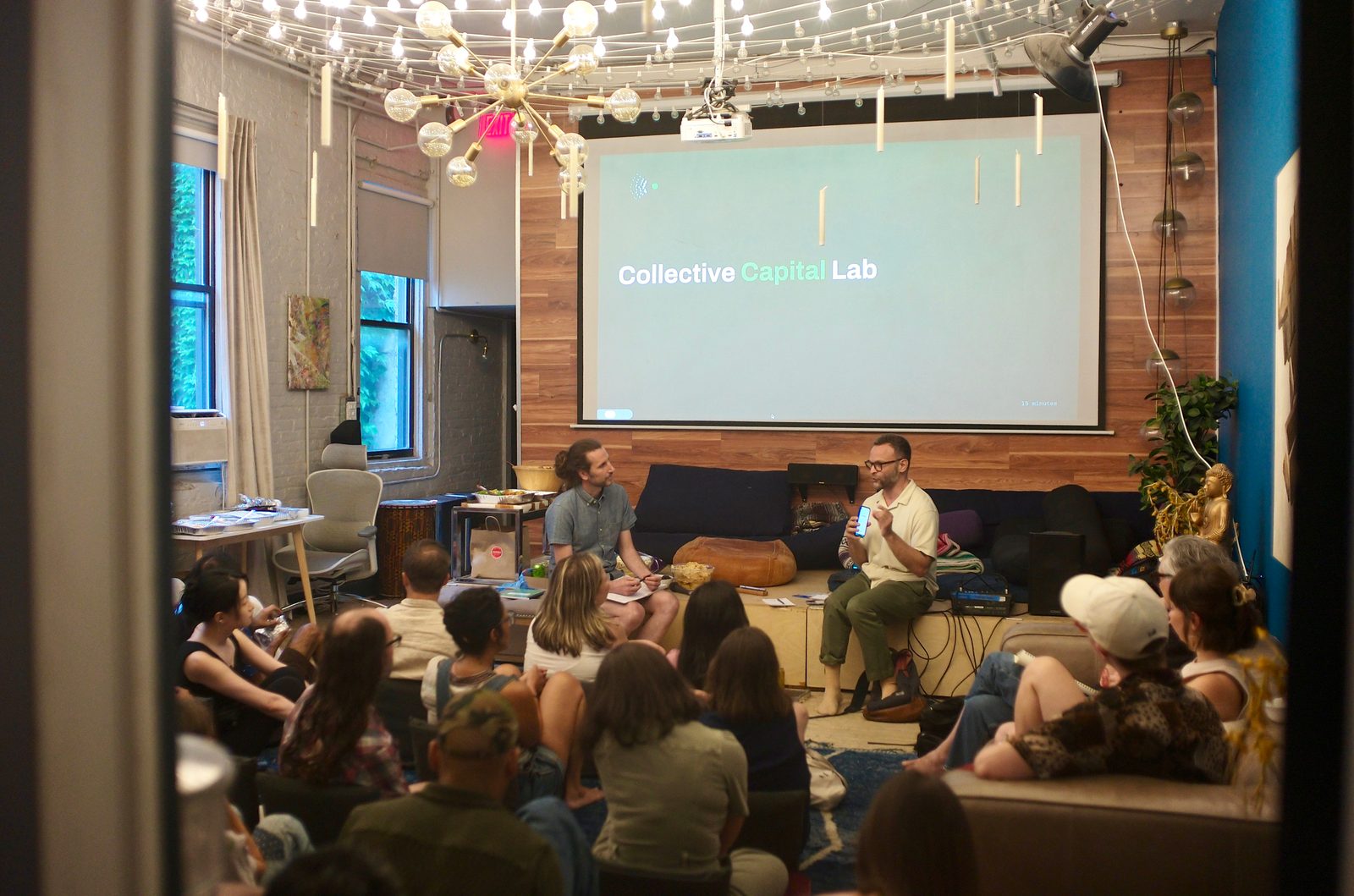 The room seen from the doorway as the workshop opens, the Collective Capital Lab title slide lit on the far wall.