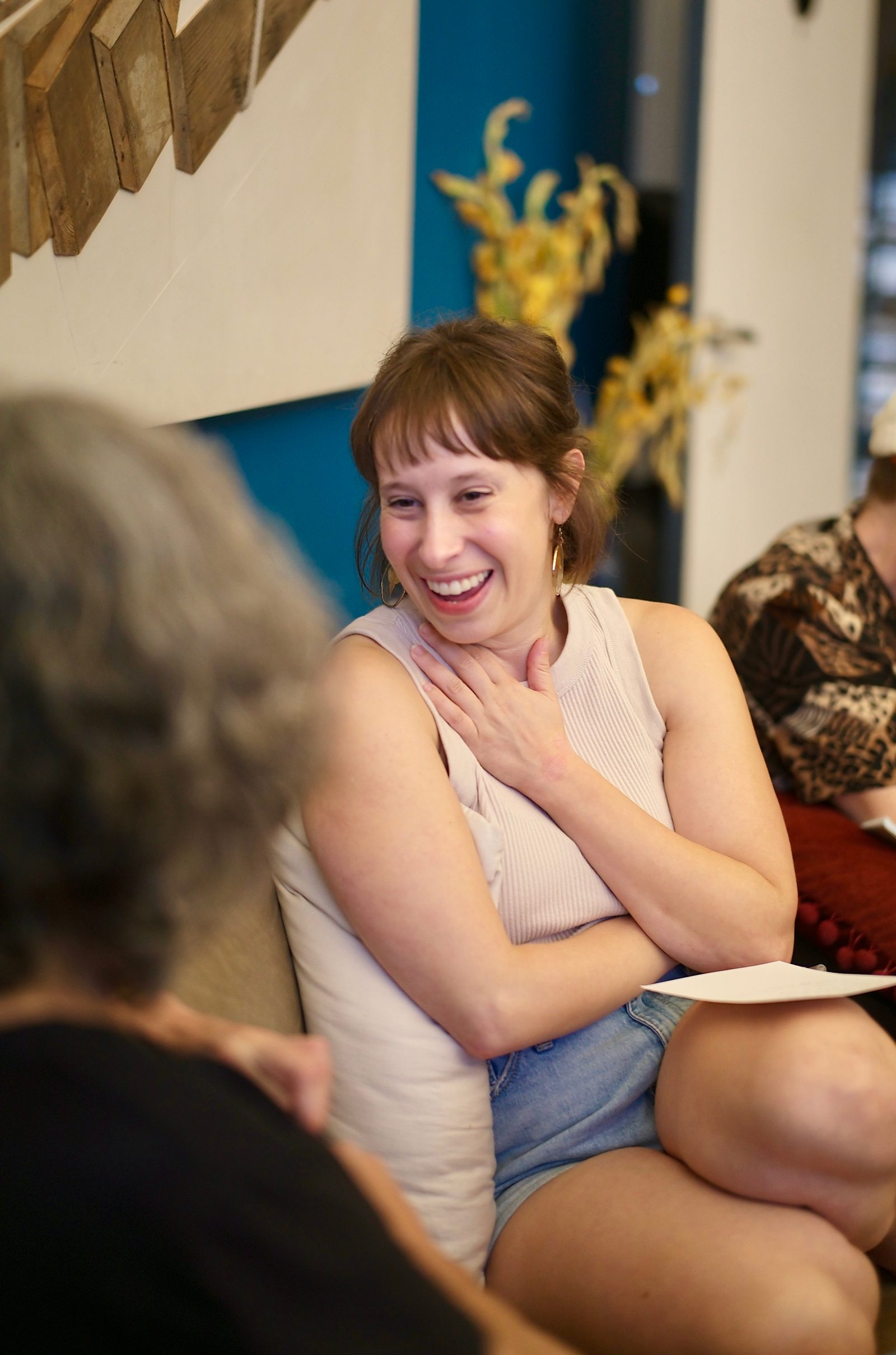 An attendee laughing mid-conversation, hand to her chest, during the opening round.