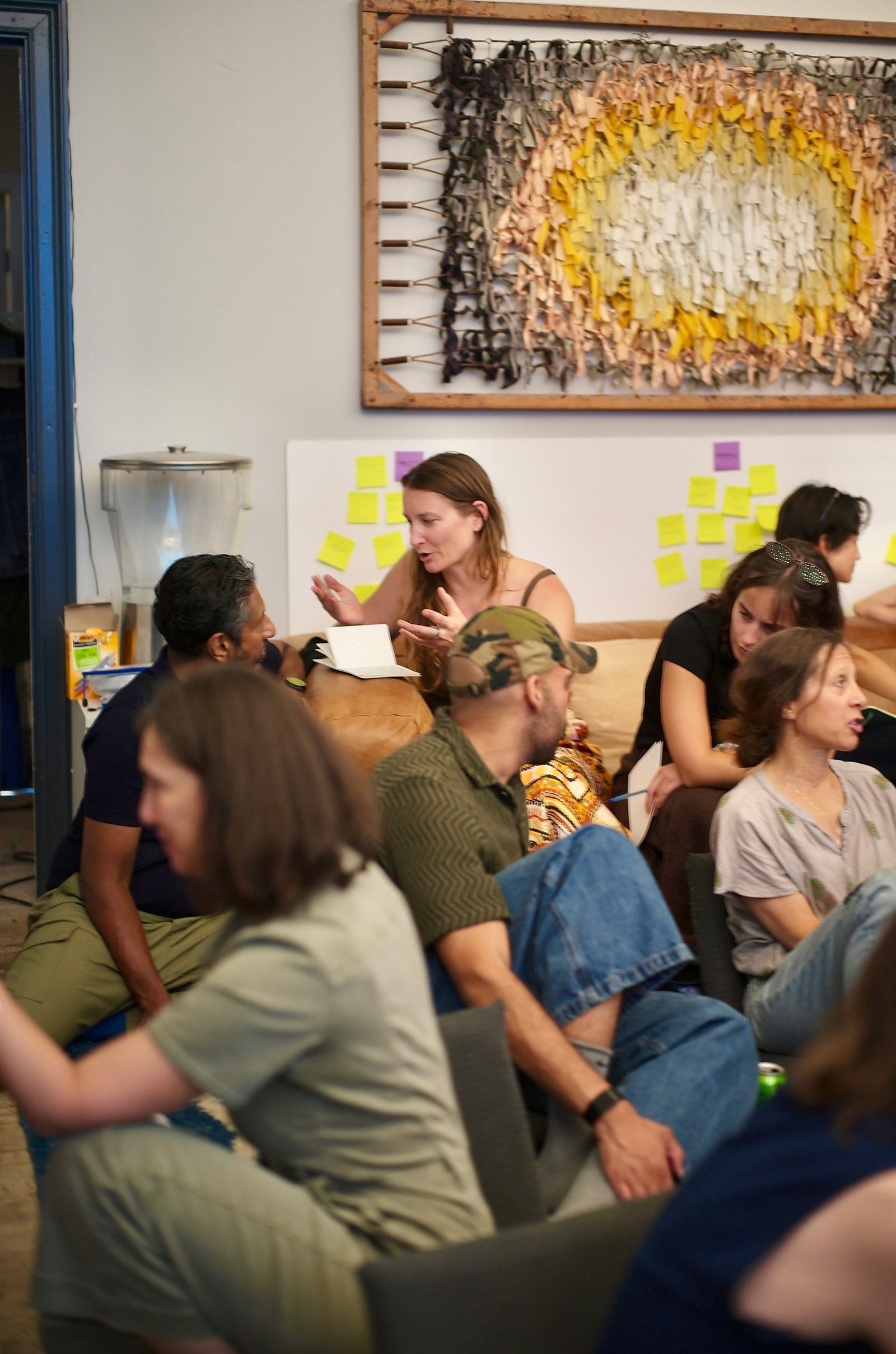 A breakout group works in front of a wall of sticky notes, one member standing to make a point.