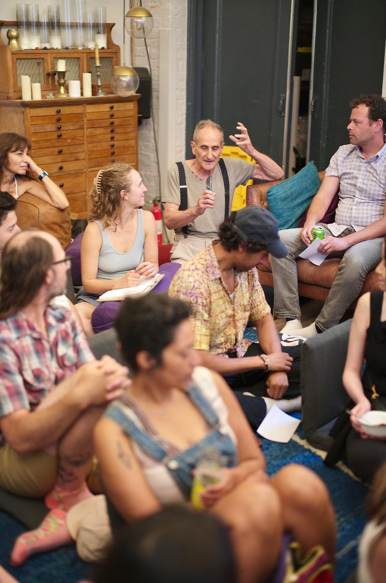 The room packed onto couches and the floor, listening through a shareback.