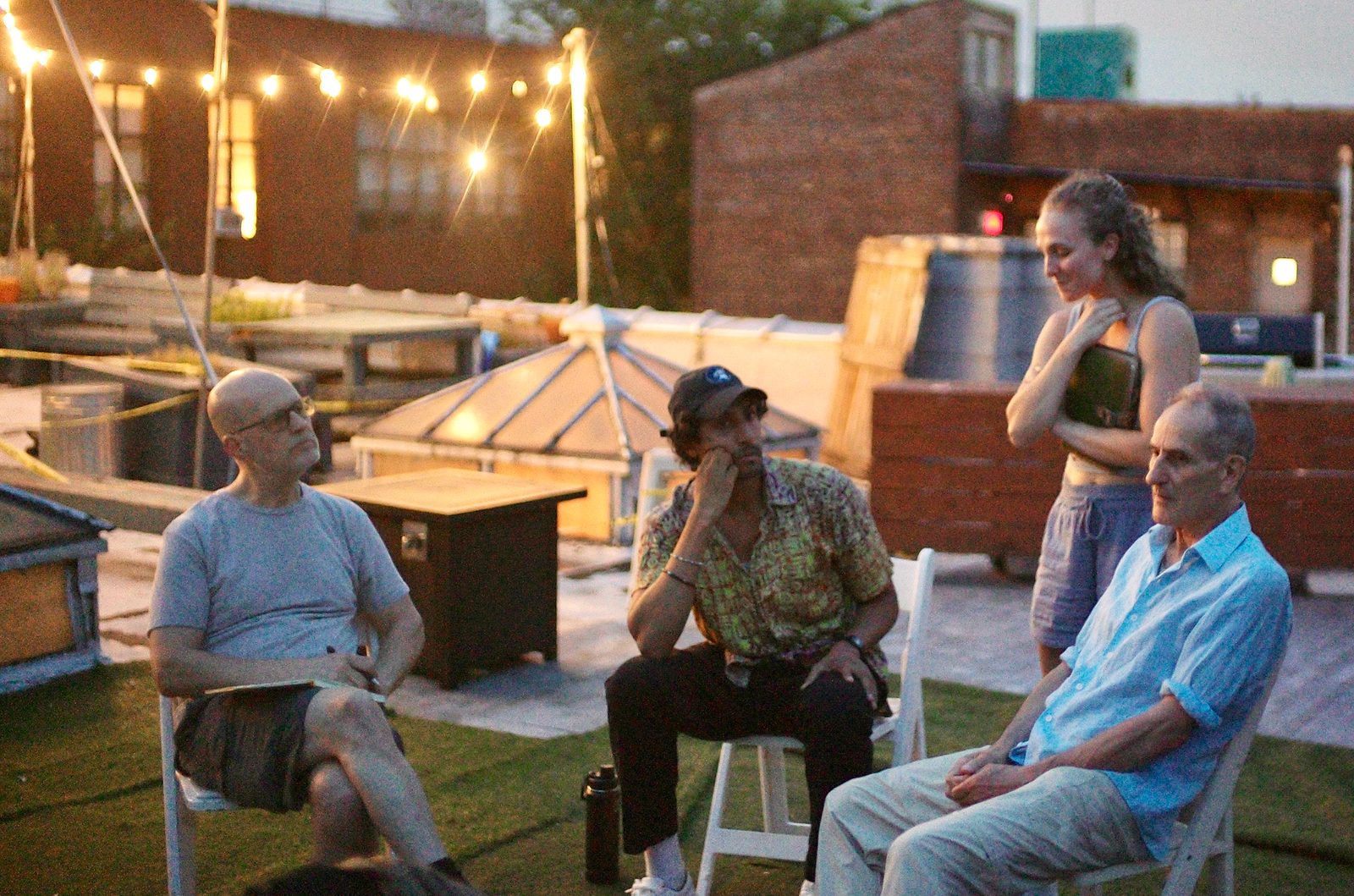 Up on the roof at dusk under string lights, a few people still talking it through after the close.