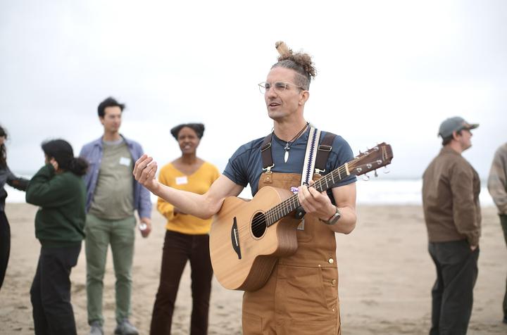 Dominic leads a song on the beach