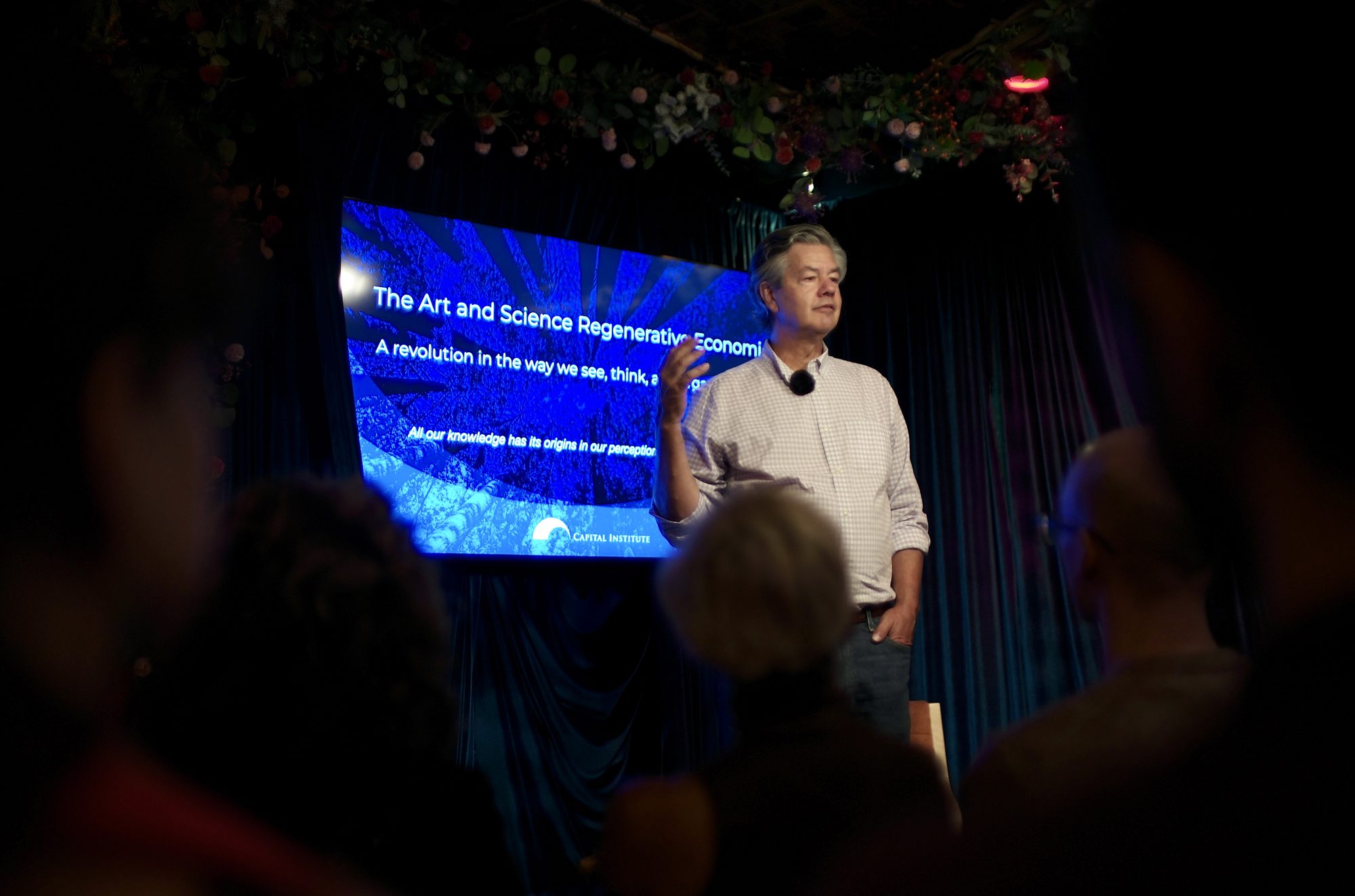 John Fullerton at the front of the back room with his title slide behind him, a revolution in the way we see, think and organize society.