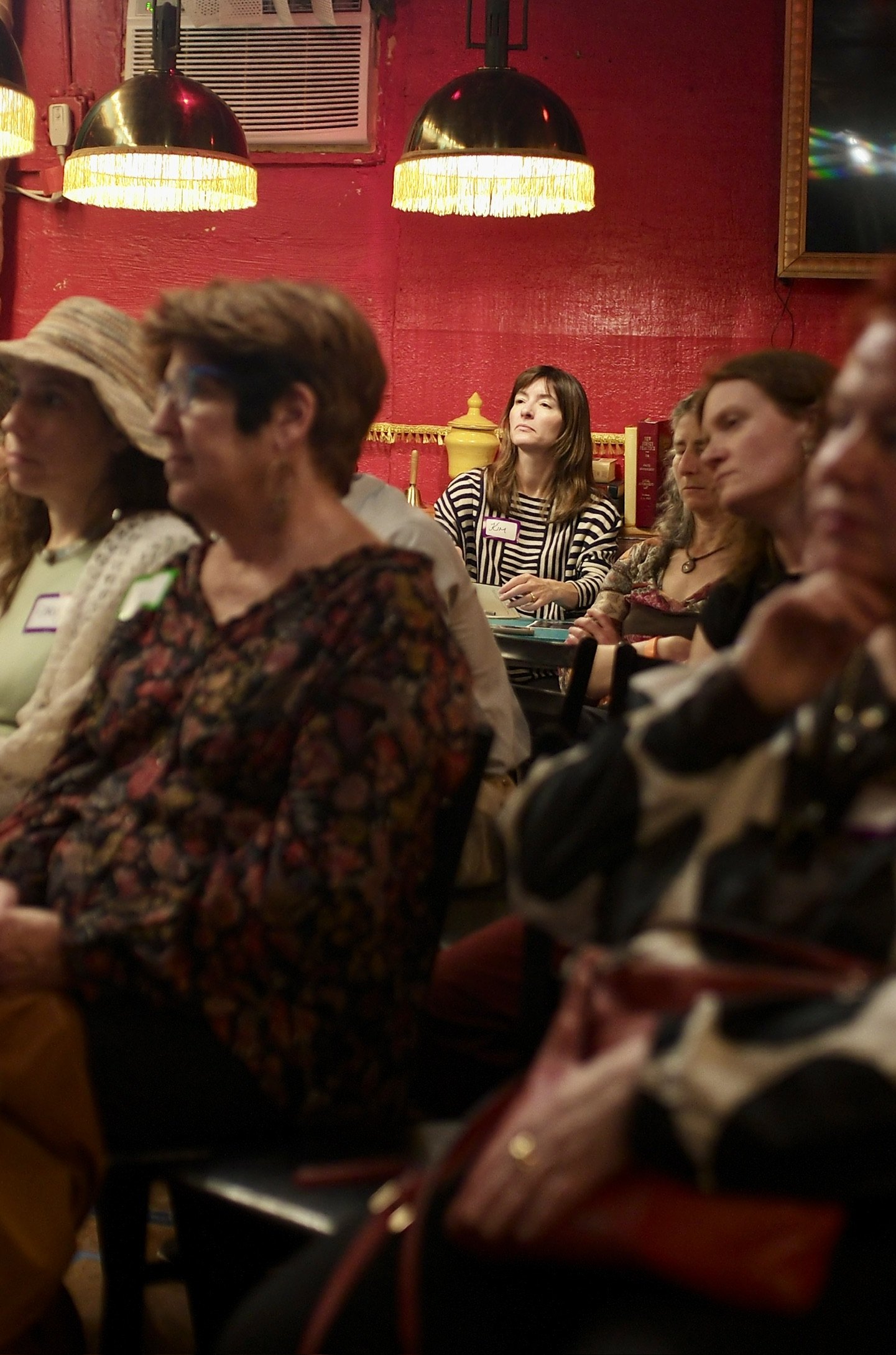 A listener in the front row, arms folded, the rest of the row soft behind her.