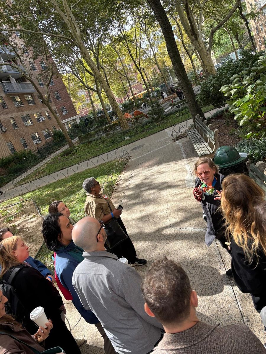The group gathered on a path between the Village View buildings, listening under the trees.