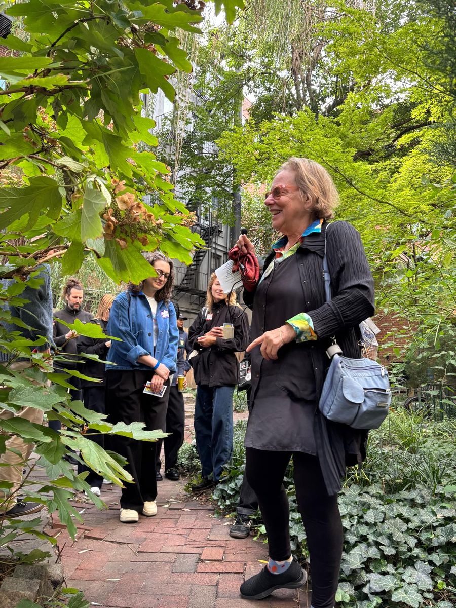 Wendy Brawer on the brick path of the Miracle Garden, walkers behind her.