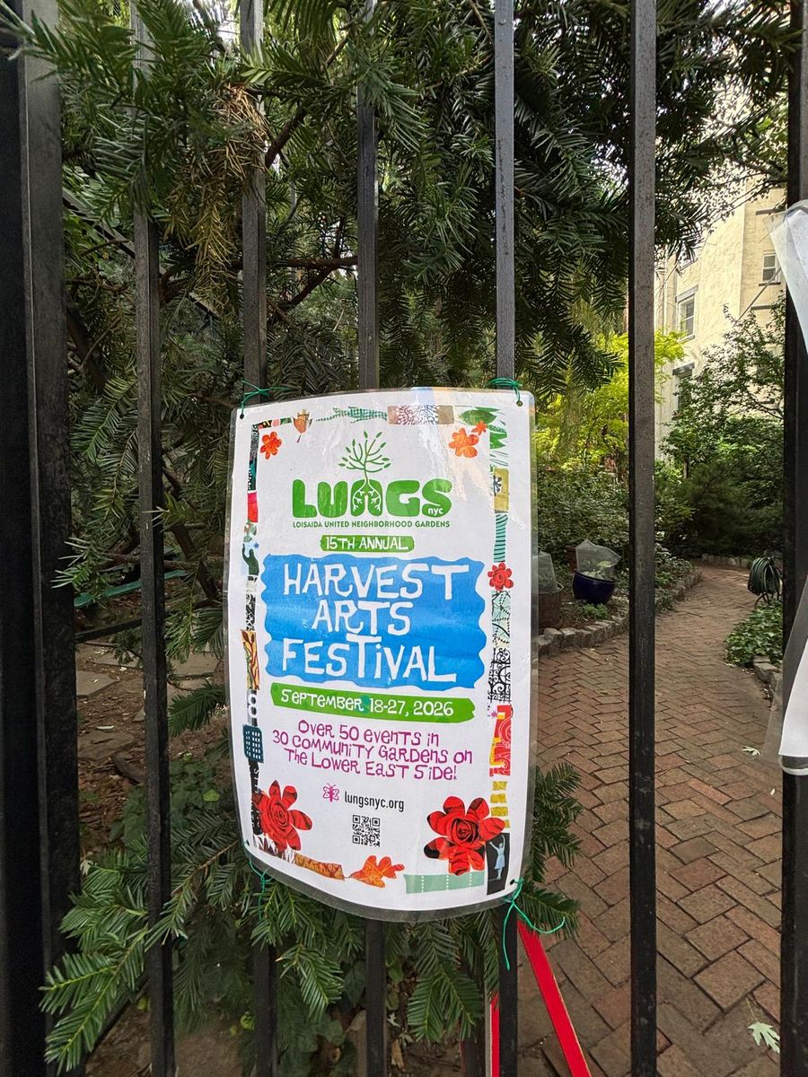 The LUNGS Harvest Arts Festival sign on the garden's iron fence.