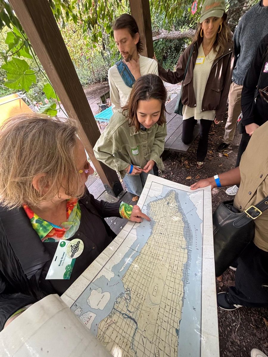 Wendy Brawer unrolling the 1609 map of Manhattan for the group under the pergola.