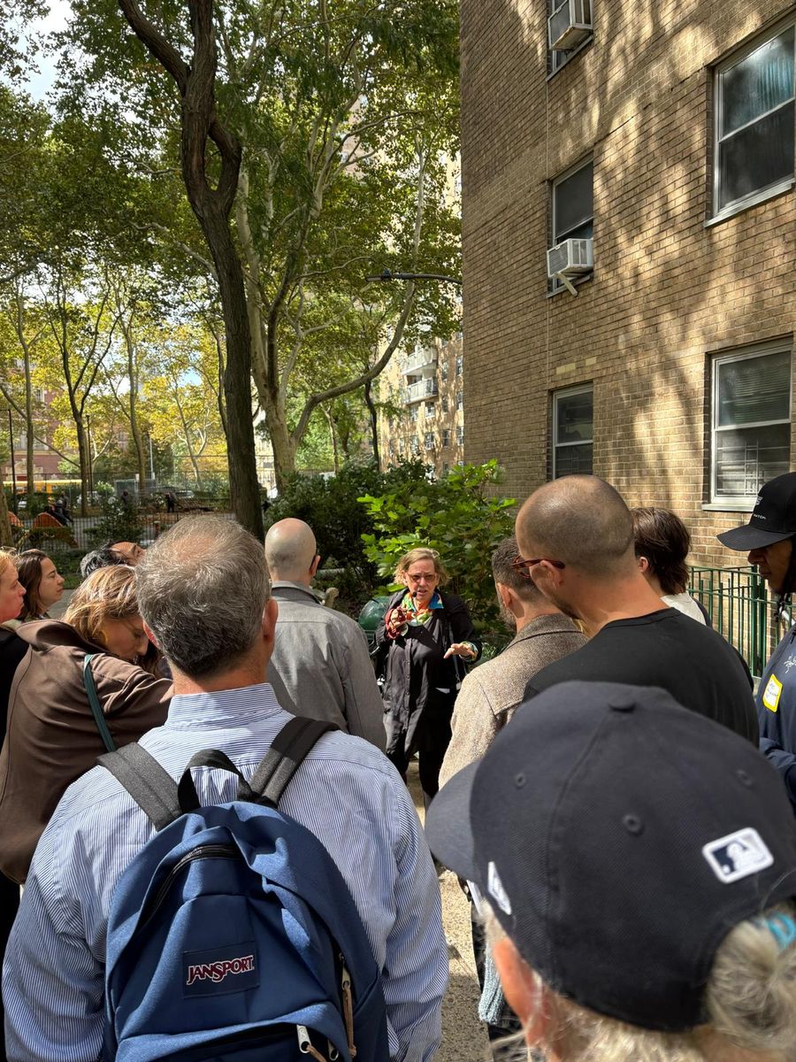 The group gathered under the trees between the Village View buildings, listening.
