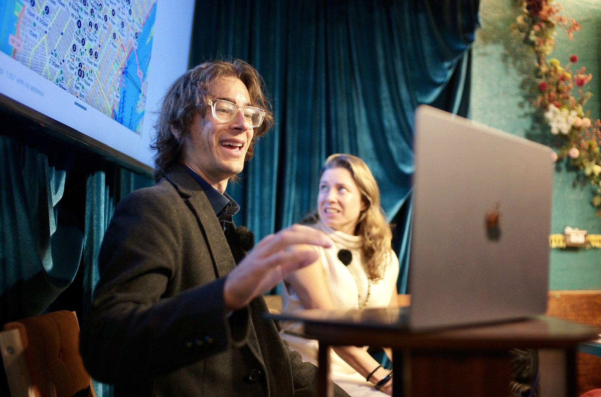 The demo at the laptop, the Climate Week map on the screen behind, a colleague smiling beside it.
