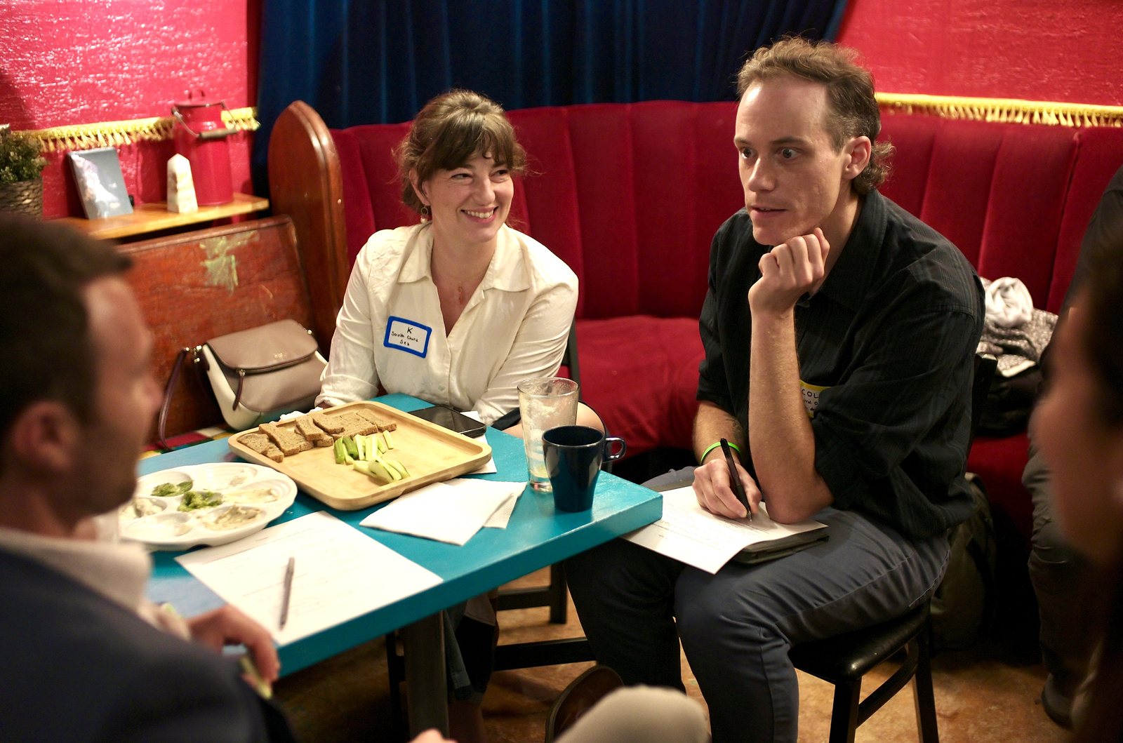 Two members of a working group leaning over the table, one smiling, the other chin in hand, the sacrificial list on the table.