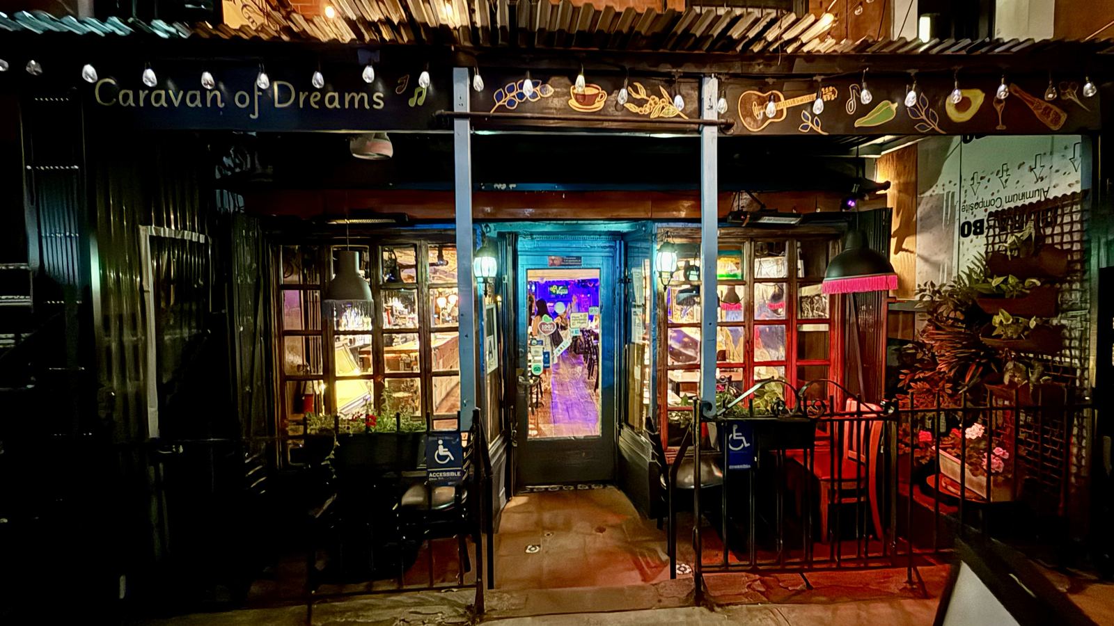 The Caravan of Dreams storefront at night, string lights on
