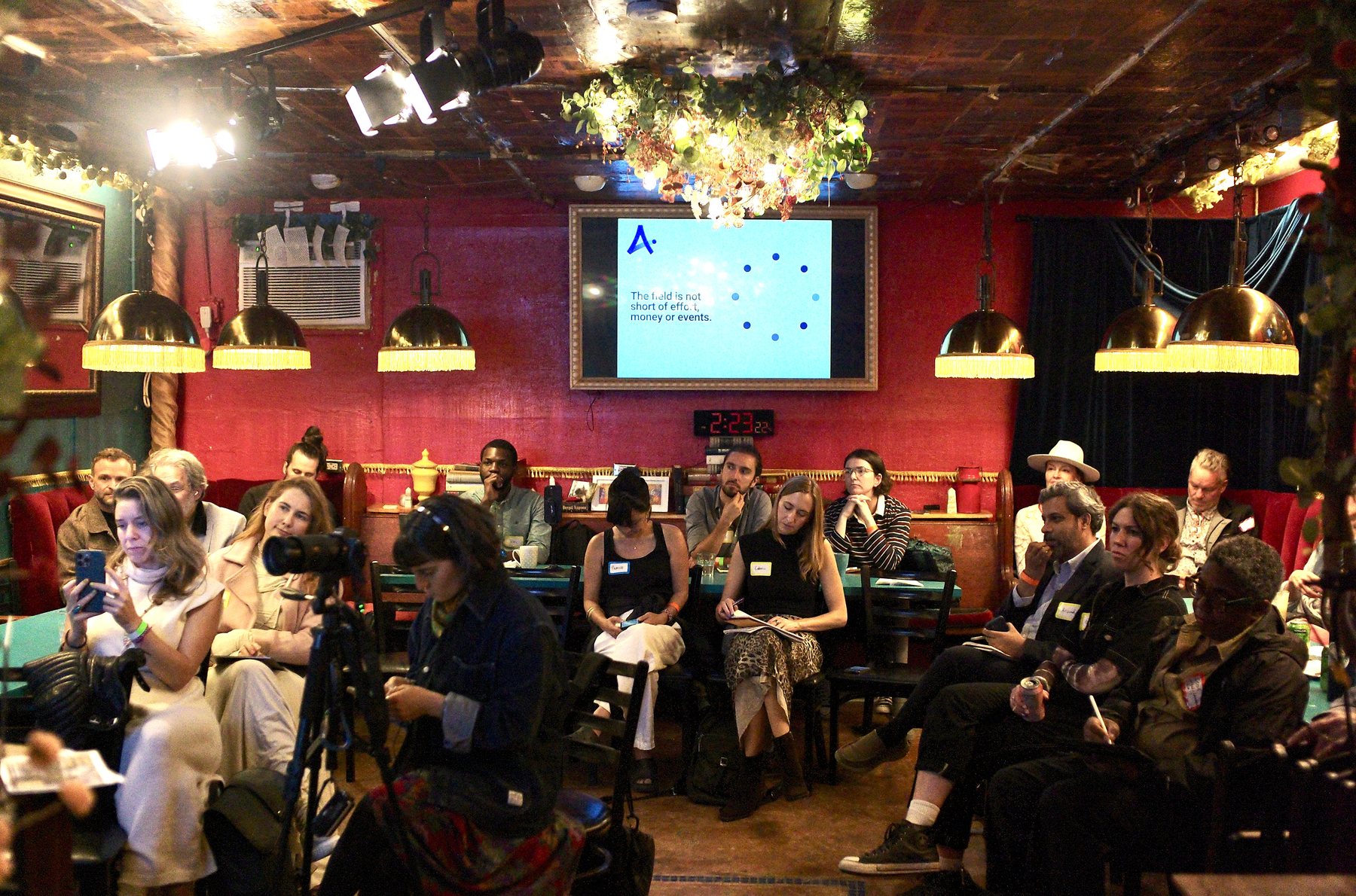 A talk in the Dream Room: slides on the main screen, guests seated at the teal tables under brass fringed lamps