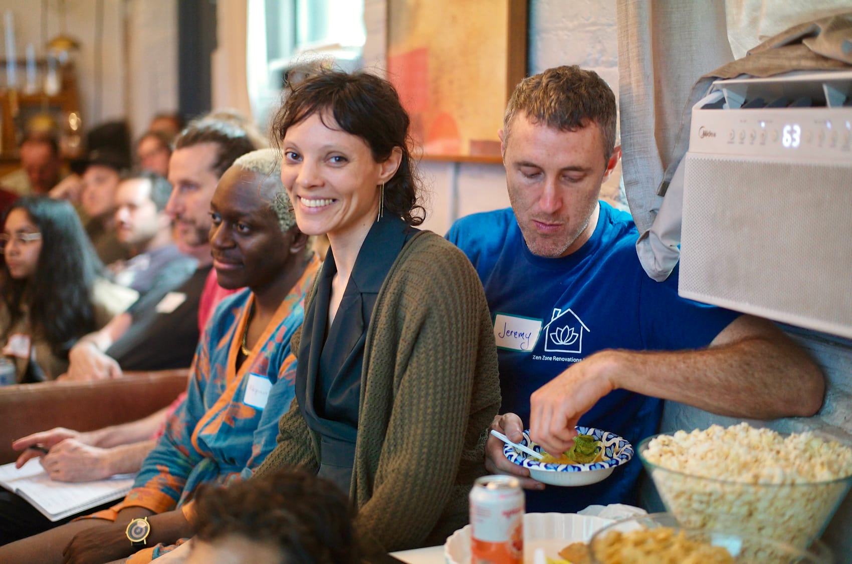 The room mid-laugh during the opening, couches full, popcorn and seltzers in reach.