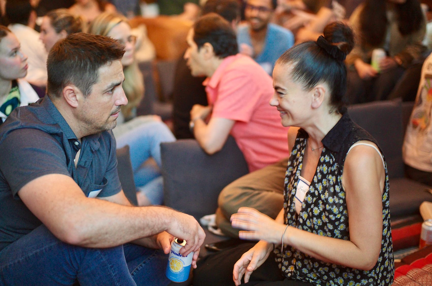 Two attendees knee to knee in the breakout, one laughing mid-sentence.
