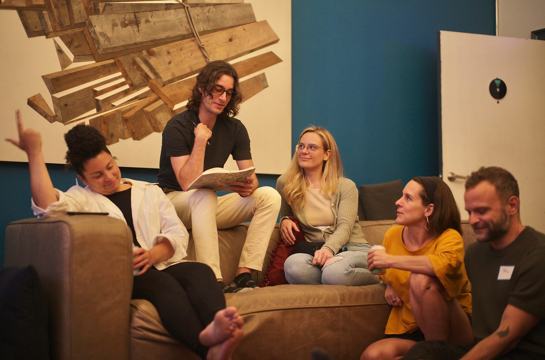 A war-games group builds its plan from the couches, one member reading the scenario off a notepad while the others weigh in.