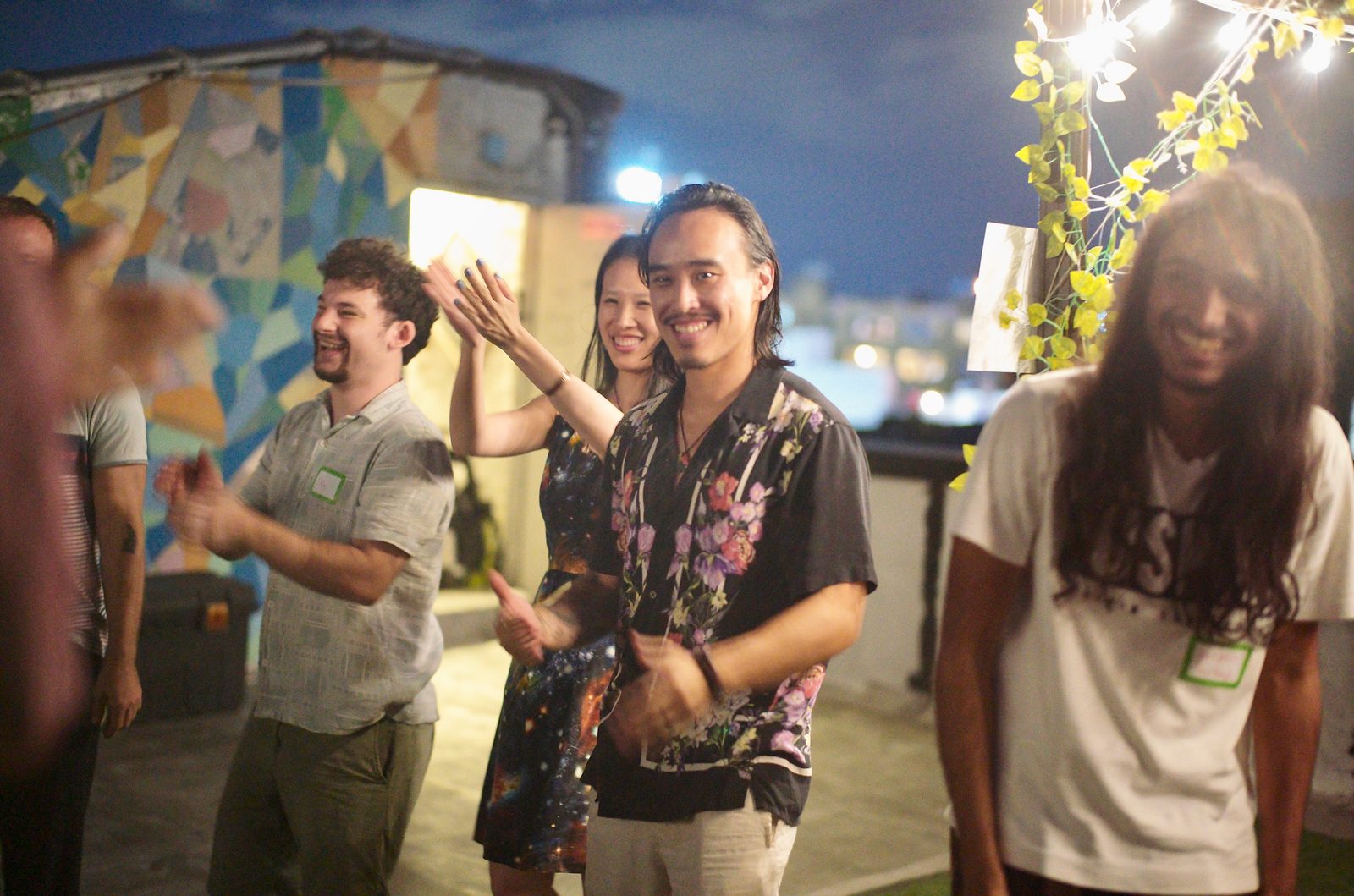 The rooftop circle laughing together in front of the mosaic wall.