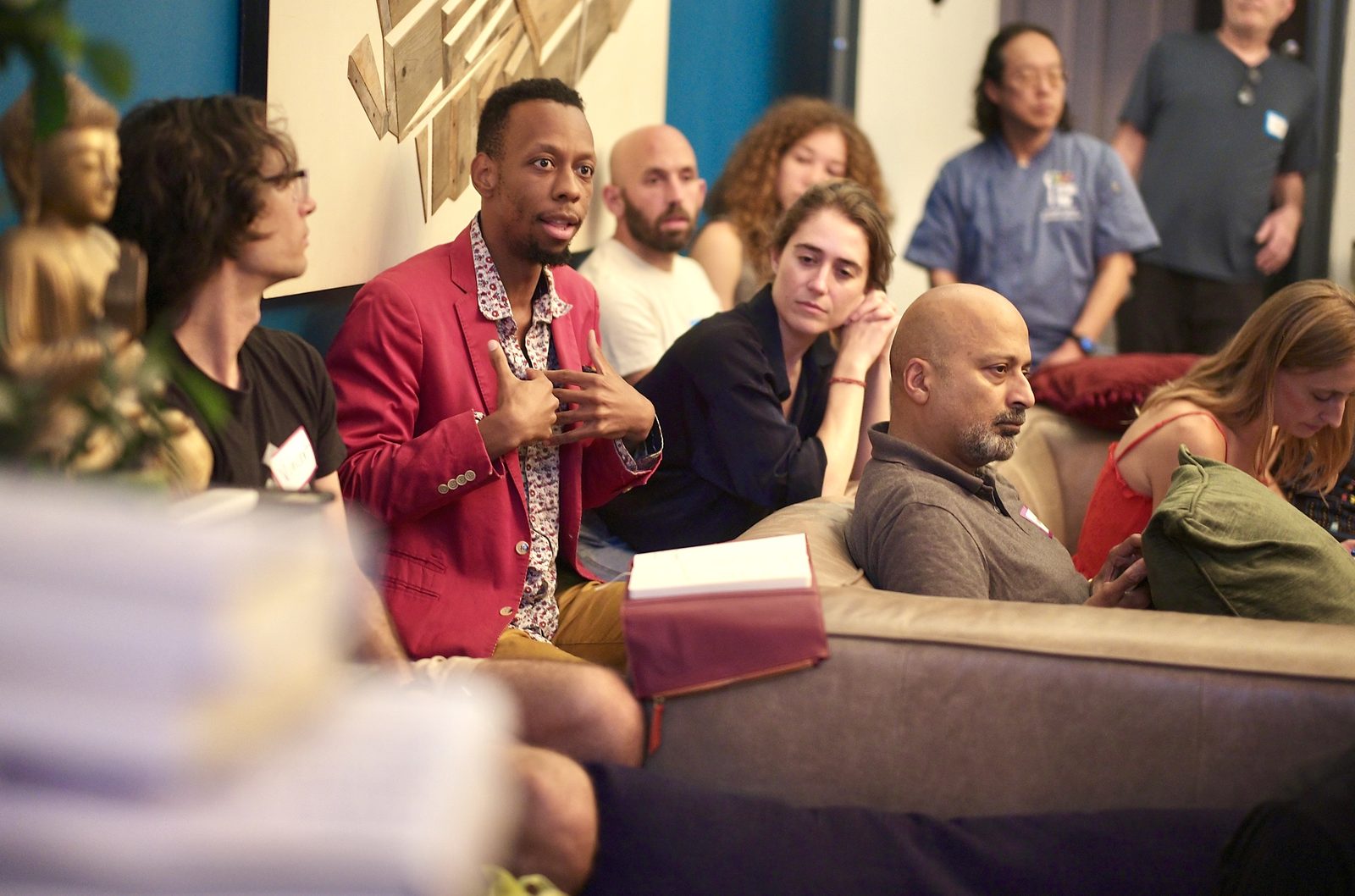 A man in a red jacket answering from the floor into the microphone, with the room turned toward him.