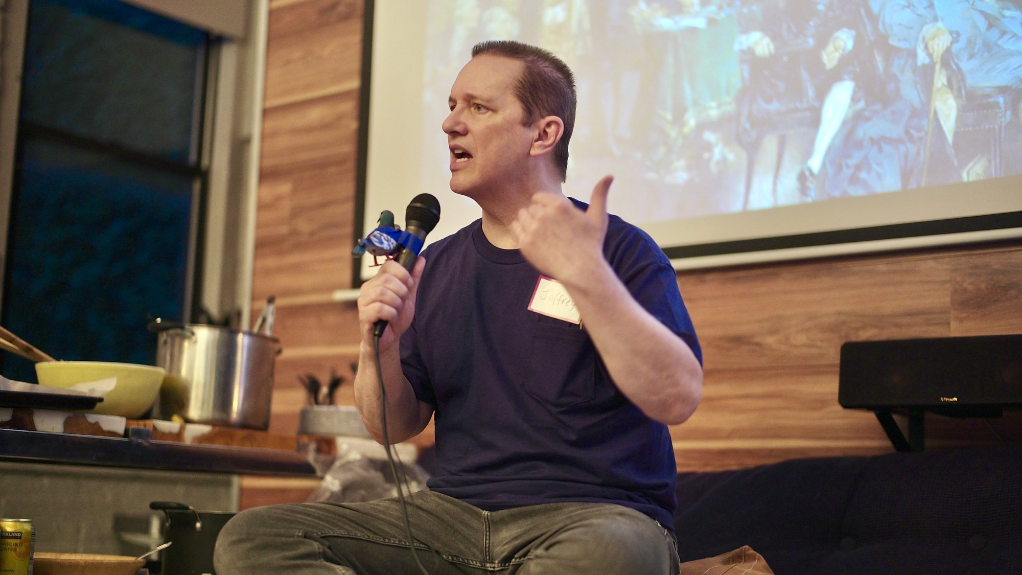 Jeffrey Winters mid-talk, the room seated on every surface under the string lights.